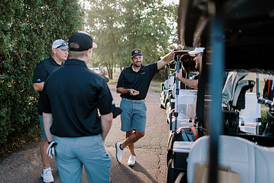 Men talking next to golf carts